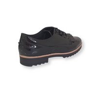 Black patent leather lace-up brogue with fringe detail and chunky sole, side angle view