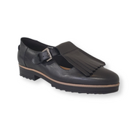 Black leather loafer with buckle strap and fringe detail, low heel, and rubber sole