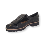 Black patent leather loafer with fringe detail and low heel on black background