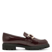 A single burgundy patent leather loafer with a gold-tone horsebit buckle and a chunky black lug sole, shown in profile against a solid green background.