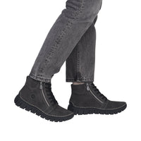 A person wearing dark gray jeans and black ankle boots with side zippers, shown from the knees down against a plain white background.