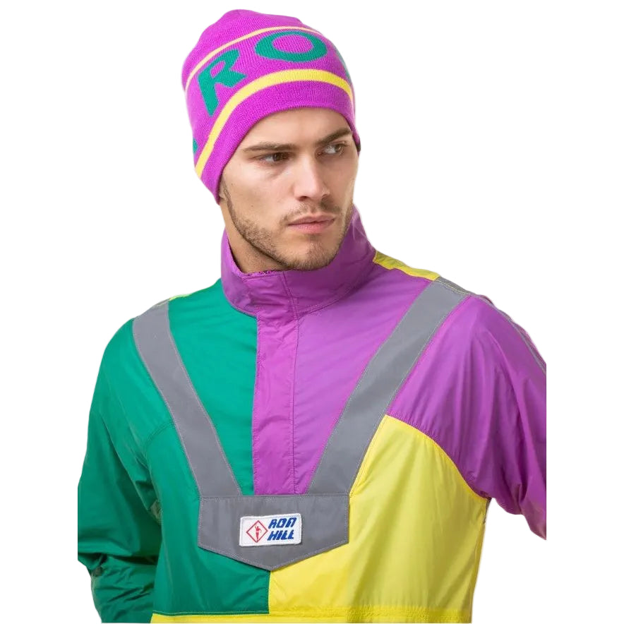 Man wearing a colorful retro windbreaker jacket and purple beanie with bold text design.
