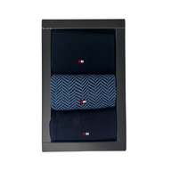 Boxed set of three navy men’s socks, one pair with blue herringbone pattern and small flag logo.
